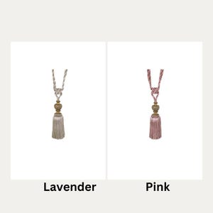 May include: Two curtain tiebacks with tassels. The tieback on the left is lavender and the tieback on the right is pink.