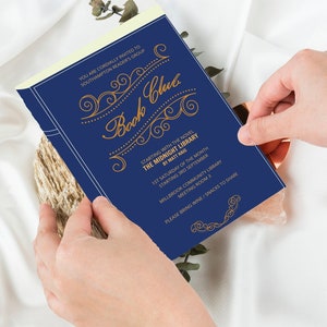Peut inclure: Une invitation de club de lecture bleu marine avec des lettres dor&eacute;es et des ornements d&eacute;coratifs. Le texte indique "Book Club" et "The Midnight Library" de Matt Haig. L'invitation est tenue par des mains sur une surface claire.