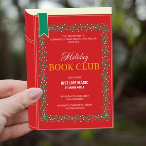 Op de afbeelding: Een rode uitnodiging voor een Holiday Book Club, met de tekst "Holiday Book Club" en details over een discussie over "Just Like Magic" van Sarah Hogle. De uitnodiging heeft een groen lint en een decoratieve rand.