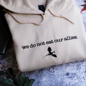 a white sweatshirt with the words we do not eat our alleas on it