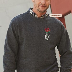 a man wearing a sweater with a rose on it