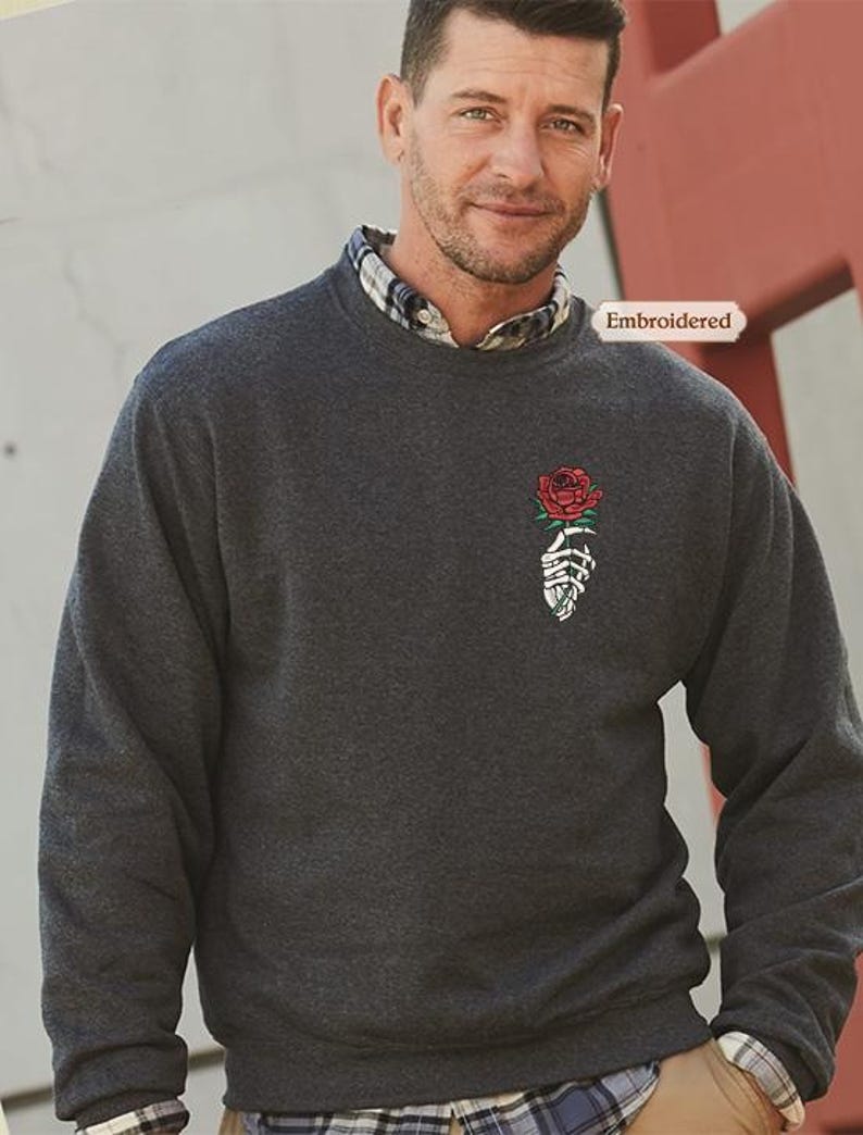 a man wearing a sweater with a rose on it