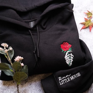 a black hoodie with a red rose embroidered on it