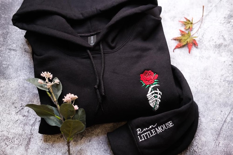 a black hoodie with a red rose embroidered on it