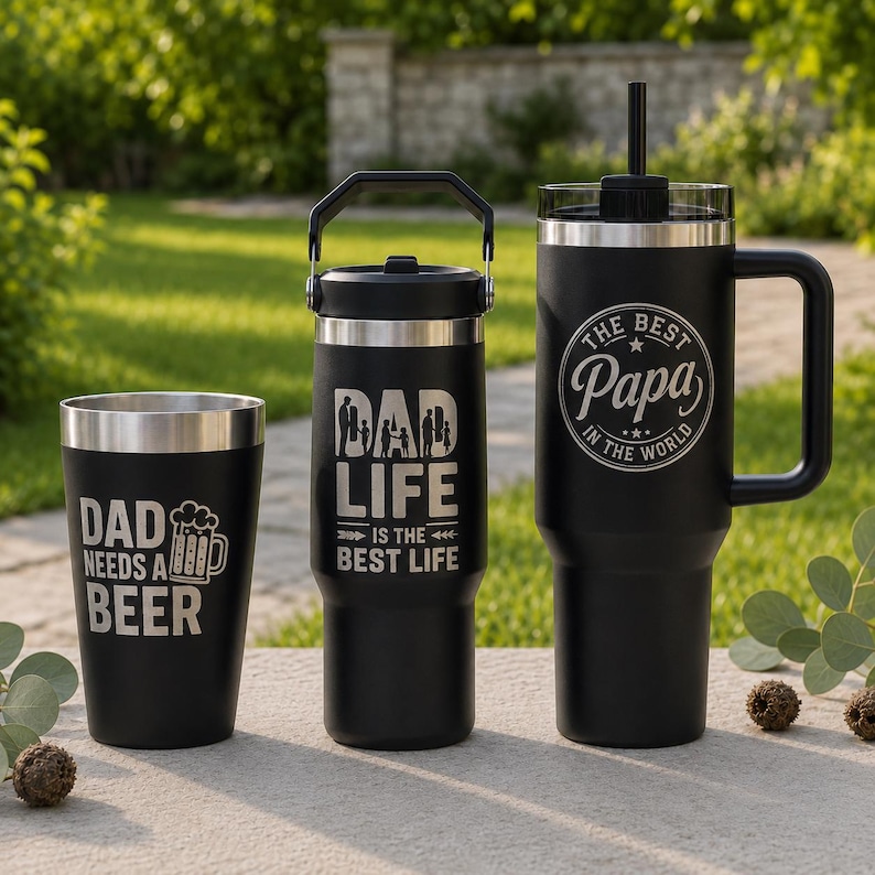 May include: Three matte black stainless steel drink containers. The left tumbler reads DAD NEEDS A BEER with a beer mug icon. The center bottle reads DAD LIFE IS THE BEST LIFE. The right tumbler features a handle, straw, and THE BEST PAPA IN THE WORLD.