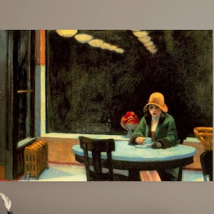 May include: A framed print of Edward Hopper's "Nighthawks" painting. The artwork depicts a woman in a green coat and hat seated at a table in a diner. The diner has a large window and a dark interior. A vase of red flowers sits on the counter.
