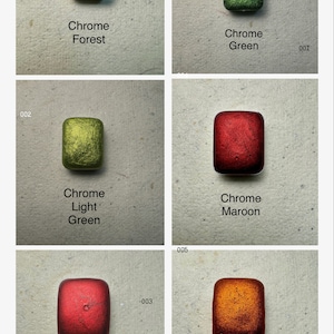 Puede incluir: Seis peque&ntilde;os recipientes cuadrados de pintura met&aacute;lica en varios colores, incluyendo verde bosque, verde claro, rojo, granate, naranja y verde cromo. Los recipientes est&aacute;n etiquetados con el nombre del color y "Chrome" en texto blanco.