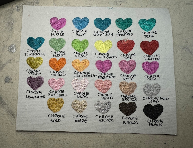 Puede incluir: Una tabla de 20 colores diferentes de pintura cromada, cada color est&aacute; representado por una forma de coraz&oacute;n. Los colores incluyen morado, azul, azul claro, esmeralda, turquesa, turquesa, verde bosque, verde, verde claro, rojo, marr&oacute;n, amarillo, naranja, naranja claro, berenjena, rosa, rosa, lavanda, oro rosa, lila, melocot&oacute;n, bronce, plomo, oro, beige, plata, marr&oacute;n y negro.