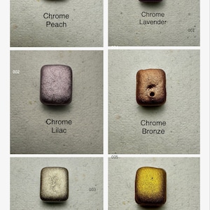 Puede incluir: Seis peque&ntilde;as muestras cuadradas de pintura met&aacute;lica en varios colores, incluyendo melocot&oacute;n, lavanda, lila, bronce, beige y oro. Cada muestra est&aacute; etiquetada con el nombre del color y la palabra "Chrome".