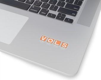 Può includere: Un adesivo con la parola "VOLS" in lettere arancioni su sfondo bianco. Le lettere sono contornate di nero e hanno piccole linee bianche sotto, che ricordano le prese elettriche.