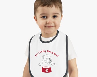 May include: White baby bib with a gray trim. The bib has a cartoon bulldog with a red bowl and the text "Let The Big Dawg Eat!"