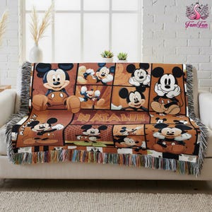 A Mickey Mouse-themed throw blanket with the name Natalie printed on it, placed on a white couch.