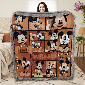 A woman is holding up a Mickey Mouse-themed blanket with the name Natalie printed on it.