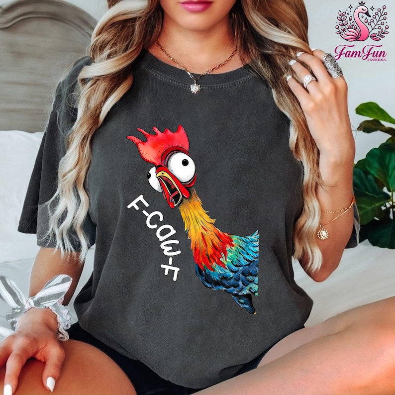 A woman wearing a black t-shirt with a colorful graphic of a rooster and the text "F-CauF" printed on it.