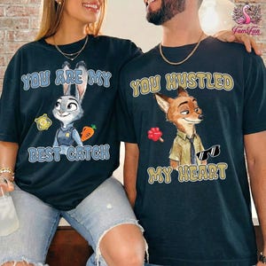 A man and a woman wearing matching t-shirts with cartoon animal characters and text.