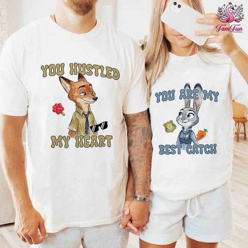 A man and a woman wearing matching white t-shirts with cartoon animal characters and text printed on them.