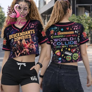May include: Two women wearing black baseball-style crop tops with the text "Descendants Zombies" and "World Collide Concert Tour." The tops have a colorful graphic design and pink trim. One woman wears black shorts with the number "66."