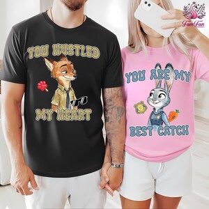 A man and a woman are standing together, both wearing t-shirts with cartoon animal characters and text.