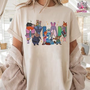 A person wearing a white t-shirt with a colorful graphic design featuring cartoon characters and the name "Dylan".