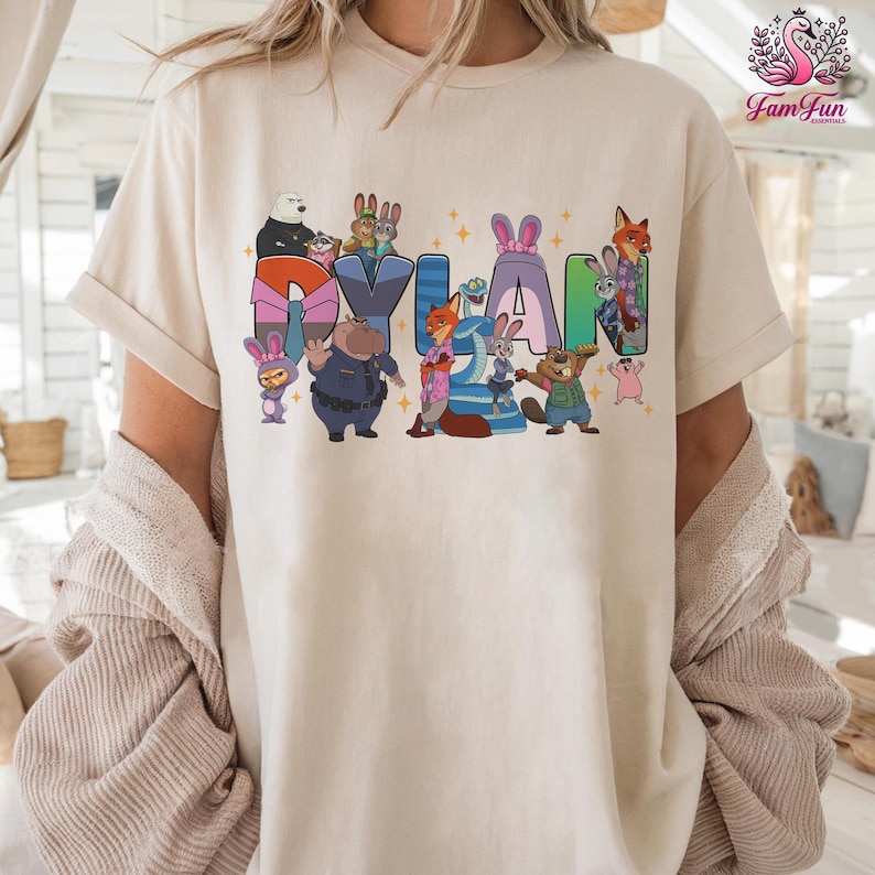 A person wearing a white t-shirt with a colorful graphic design featuring cartoon characters and the name "Dylan".