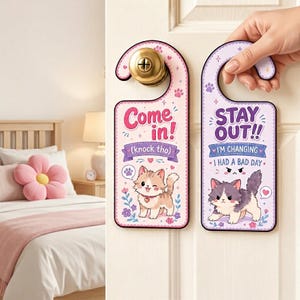 Pode incluir: Dois cabides de porta decorativos com ilustrações de gatos. Um diz "Come in!" e o outro "Stay out!! I'm changing - I had a bad day." Ambos têm um esquema de cores rosa e roxo com pegadas e detalhes florais.