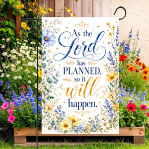 Könnte beinhalten: Eine rechteckige Gartenflagge mit weißem Hintergrund und einem floralen Rand aus blauen, gelben und weißen Wildblumen. Der Text lautet, As the Lord has PLANNED, so it will happen, in blauer Schreibschrift und goldener Schrift.