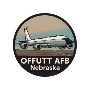 May include: A circular sticker featuring a stylized illustration of a white and gray airplane in flight. The sticker has a black border and includes the text "OFFUTT AFB Nebraska" in white letters.