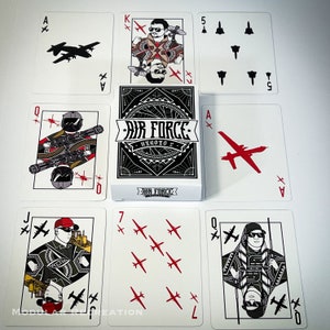 May include: A set of playing cards featuring a military theme. The cards are red and black with a white background. The cards feature illustrations of fighter jets, soldiers, and the words "Air Force Heroes".