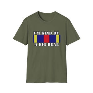 May include: A green t-shirt with the text "I'm kind of a big deal" and a graphic of a military ribbon with yellow, blue, and red stripes.