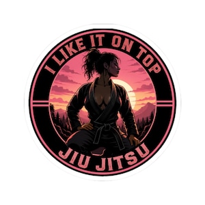 May include: A circular sticker featuring a person in a black martial arts gi with a belt, set against a sunset mountain landscape. The text I LIKE IT ON TOP JIU JITSU is printed in pink along the black border of the circular design.
