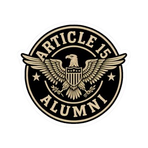 May include: A circular sticker with a black background and a beige border. The sticker features a detailed illustration of an eagle with outstretched wings, a shield, and the text "ARTICLE 15 ALUMNI" in a circular arrangement.