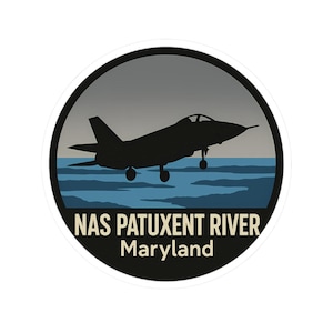 May include: A round sticker featuring a black silhouette of a jet taking off over blue water. The background shows a gray sky. The text "NAS PATUXENT RIVER Maryland" is printed in white.