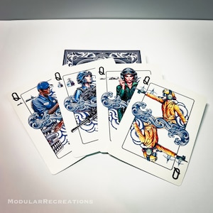 May include: Four playing cards, each featuring a queen with a different profession. The queens are depicted in a stylized, cartoon-like style with blue and white clouds and waves behind them. The cards are all face up and arranged in a fan shape.