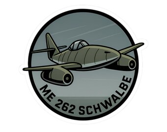 May include: A sticker depicting a cartoon illustration of a Messerschmitt Me 262 Schwalbe jet fighter. The aircraft is olive green with black detailing, set against a grey background within a black-bordered circle. The text "ME 262 SCHWALBE" is printed in white.
