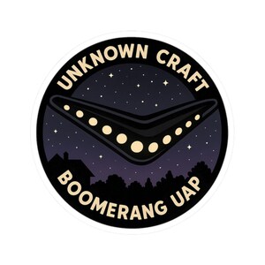 Könnte beinhalten: Runder Aufkleber mit dem Text "UNKNOWN CRAFT BOOMERANG UAP". Das Bild zeigt einen schwarzen Bumerang mit leuchtenden Punkten vor einem Sternenhimmel, mit einer Silhouette von Bäumen und einem Haus im Hintergrund.
