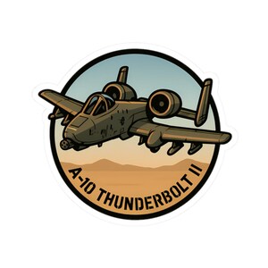 May include: A sticker featuring a cartoon illustration of an A-10 Thunderbolt II aircraft in flight. The aircraft is olive green with black accents, set against a desert landscape and a blue sky. The text "A-10 THUNDERBOLT II" is in white.