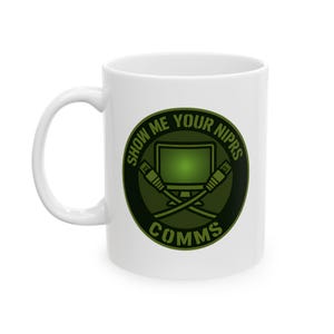 May include: White ceramic mug with a green graphic. The graphic features a computer monitor, crossed network cables, and the text "SHOW ME YOUR NIPRS COMMS" in a circular design. The mug has a curved handle.