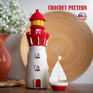 Può includere: Un faro all'uncinetto fatto a mano con dettagli rossi e bianchi, una luce gialla e una piccola barca a vela. Il faro ha un tetto rosso e un corpo bianco con piccole finestre. Il testo "CROCHET PATTERN" è visualizzato sopra il faro.