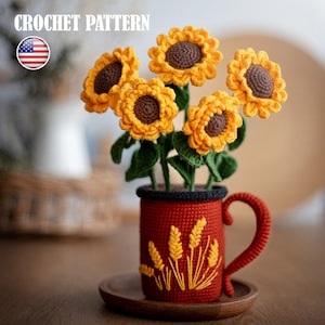 May include: Crochet pattern for a bouquet of yellow sunflowers in a red mug with wheat designs. The mug is on a wooden coaster.