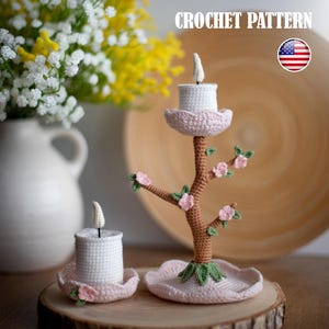 Puede incluir: Candelabros de ganchillo blancos y rosas, con un diseño en forma de árbol. Los candelabros están sobre una superficie de madera, con un jarrón de flores en el fondo. El texto "CROCHET PATTERN" es visible.
