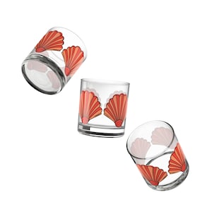 May include: Three clear glass tumblers with a red and orange seashell design. The tumblers are empty and are shown from different angles.