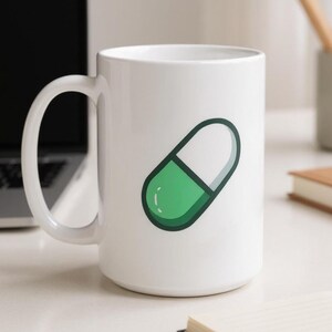 Puede incluir: Taza de cerámica blanca con un diseño de cápsula verde y blanca. La taza tiene un asa grande. El fondo incluye un portátil, lápices y un cuaderno. El diseño es una ilustración simple y limpia.