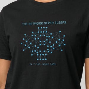 May include: Black crew neck t-shirt featuring the text "THE NETWORK NEVER SLEEPS" and a light blue network diagram. Below the graphic is the text "24·7·365·SINCE 2009".