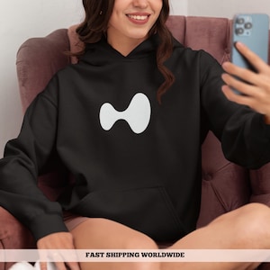 May include: Black hoodie with a white abstract design on the front. The hoodie has a front pocket and a hood. The person in the image is sitting in a pink chair and holding a phone. The text "FAST SHIPPING WORLDWIDE" is at the bottom.