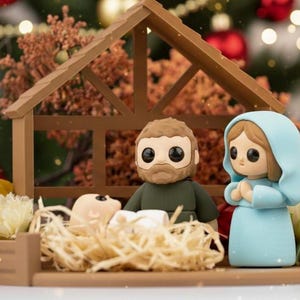 Puede incluir: Un belén en miniatura con figuras de José, María y el niño Jesús en un establo de madera. Las figuras tienen ojos grandes y están rodeadas de decoraciones navideñas, incluyendo adornos rojos y luces parpadeantes.