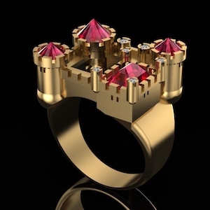 May include: A gold ring shaped like a castle with red and clear gemstones. The ring has a thick band and a detailed design.
