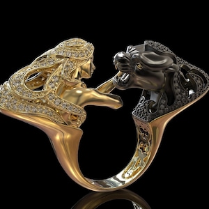 May include: A gold ring featuring a black panther head on one side and a woman's head on the other. Both sides are decorated with small diamonds.