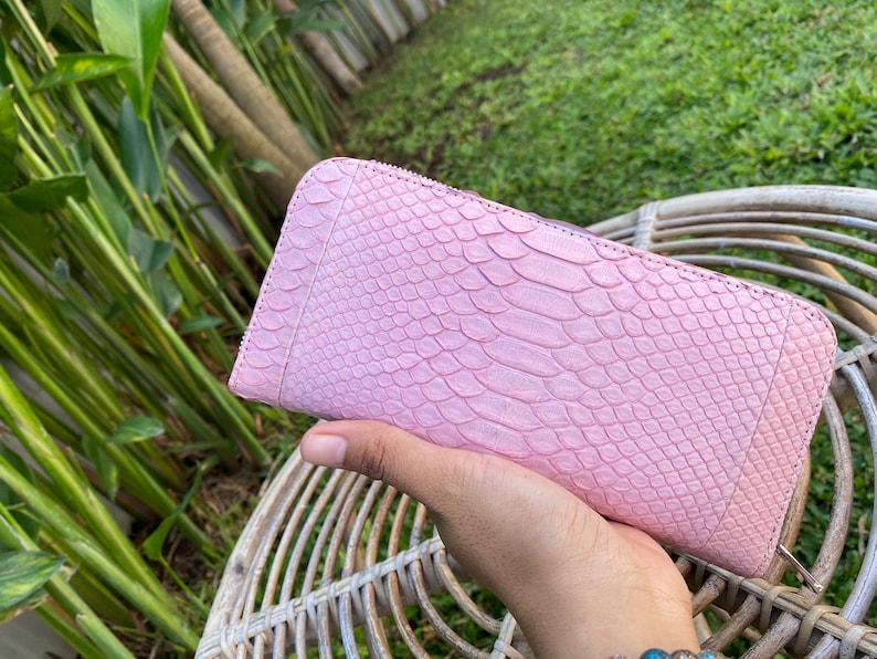 Peut inclure: Un portefeuille en cuir de serpent rose avec une fermeture &eacute;clair.