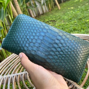 Peut inclure: Un portefeuille en cuir de serpent vert avec une fermeture &agrave; glissi&egrave;re. Le portefeuille est en cuir v&eacute;ritable et a une surface textur&eacute;e.
