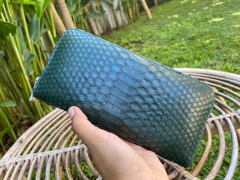 Peut inclure: Un portefeuille en cuir de serpent vert avec une fermeture &agrave; glissi&egrave;re. Le portefeuille est en cuir v&eacute;ritable et a une surface textur&eacute;e.